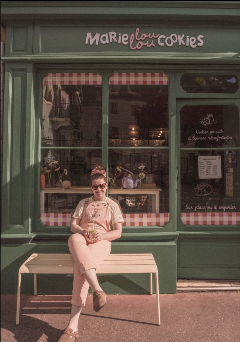 Marie-Lou assise devant sa boutique à Annecy, souriante face à l'objectif